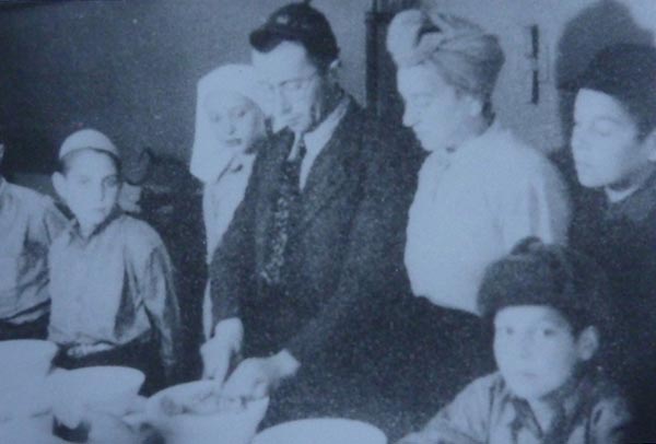 LL: Making Kiddush for Shabbat after liberation from Belsen with Mr. Birnbaum, his wife and family and others, 1945