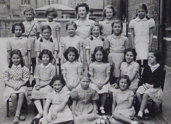 LL: South Hampstead High School, LL in the first row, second child in from the left, holding a gift from Lola: a pair of silver Dutch clogs keyring