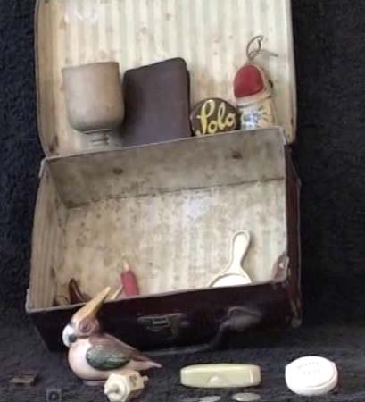 RE: Suitcase with possessions that Ruth brought to England in 1939. "This is a little Koffer which was mine which I brought with me with my own personal things, given to me by some people I cannot even remember - like a pencil sharpener like a frog, a needle case; one or two coins of Austrian money; a little bird that has a pin-cushion; a yo-yo that was given to me to learn to tie my shoes; a Hanukkah dreidl; a German dreidl. I think the Hanukkah one belonged to my grandfather, a knife that belonged to my father; an egg-cup that one of my uncles made during the war."