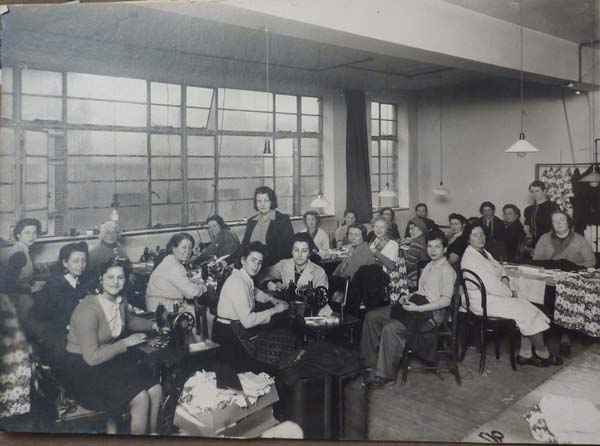 RD: Doing sewing 'war work', Bruton Street, 1945. Ruth at the very left, And Mrs. Heinzitz in the middle standing up. "She owns all that area. She, she, she had- that was her business."